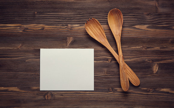 Close up wooden spoons, and blank paper on wooden board.