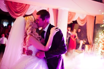 Amazing first wedding dance of newlyweds on low pink light and heavy smoke with fireworks