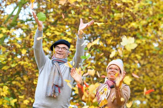 glückliches zufriedenes Seniorenpaar im Herbst, Laub werfen