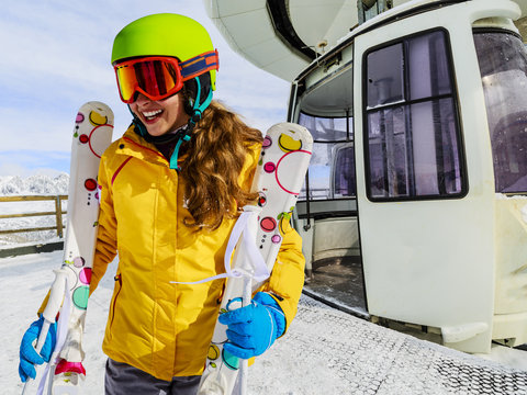 Girl teenager skier go out with ski on arms from the cable car i