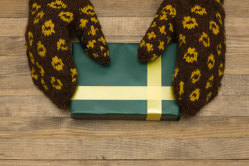 hands in mittens hold red green box