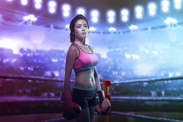 Pretty asian girl in red boxing gloves posing in the boxing ring