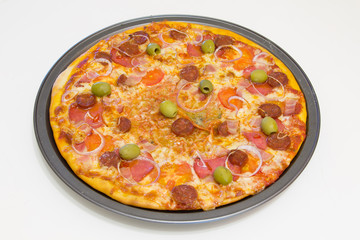 Pizza with chorizo, salami, bacon, onions and olives on a white wooden table, selective focus