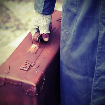 poor traveler with old worn leather suitcase