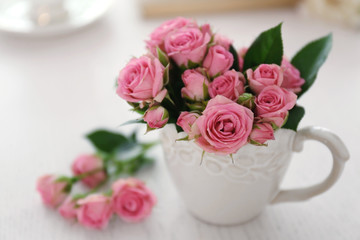 Bouquet of beautiful roses in a cup on a  table