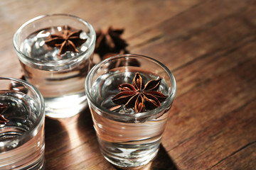 Vodka with anise on wooden background