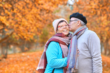 lebensfrohe Senioren küssen sich im Herbstwald