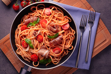 Spaghetti with amatriciana sauce and bacon in pan, top view