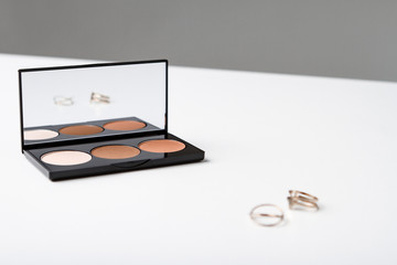 Eyeshadow and accessories on white table.