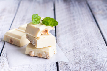 White chocolate with nut on a white wood background. Copy space