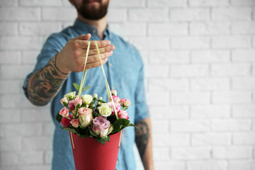 Tattooed man holding paper cone with beautiful bouquet, close up view
