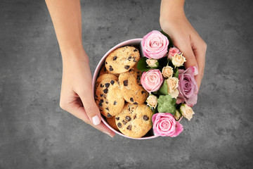Female florist preparing box with beautiful flowers and cookies, closeup