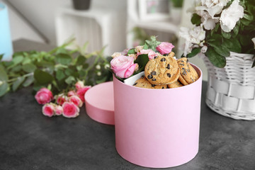 Box with beautiful flowers and cookies on dark textured table