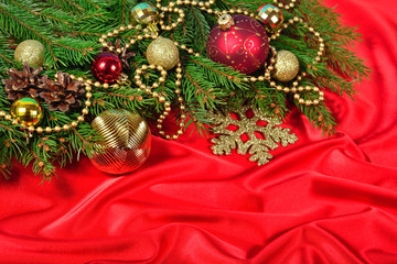 Christmas decorations and spruce branch and cones on a red