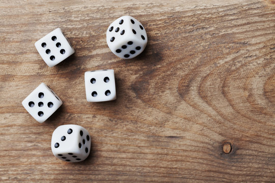 White dice on wooden table from above. Gambling devices. Game of chance concept.