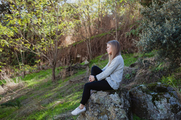 Naklejka na ściany i meble Young woman sitting on a big stone