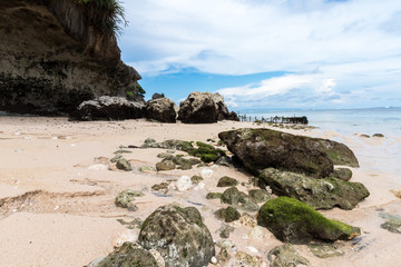 Fototapeta na wymiar Small rocks scattered on beach sand close up. Beautiful ocean landscape, amazing sky. Bali, Indonesia.
