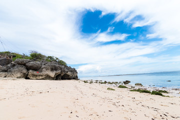 Obraz premium Small rocks scattered on beach sand close up. Beautiful ocean landscape, amazing sky. Bali, Indonesia.