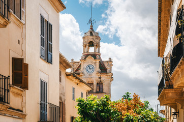 Fototapeta na wymiar Architecture of Majorca. The tower with big clock of City town hall in Old Town of Alcudia, Mallorca, Balearic island, Spain