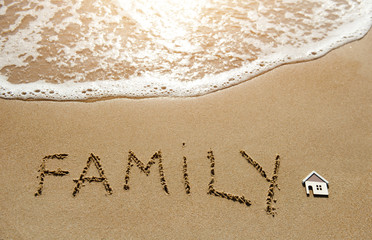 A little house and family written on the sand beach