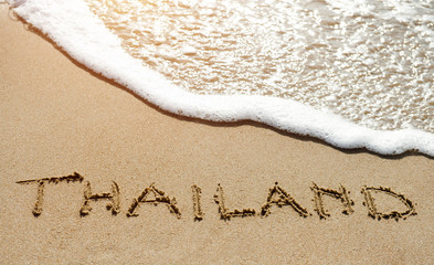 Fototapeta premium Thailand written on the sand beach near sea - travel holiday concept