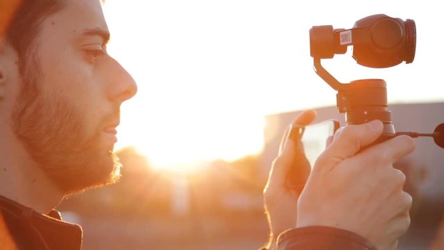 Young boy is taking video footage with a gimbal camera at the Train station