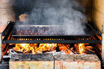 Roasting grilled Chestnuts on barbecue with flames, fire and cha