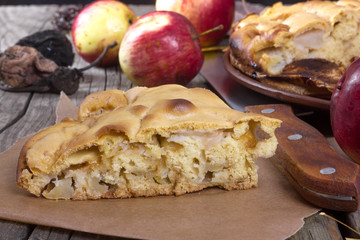 piece of apple pie on a wooden table with apples