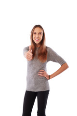 Happy toothy smiling young girl showing thumb up standing over w