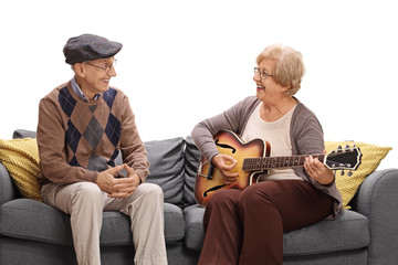 Mature man sitting on sofa and looking at mature woman playing o