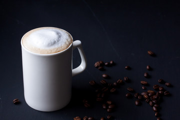 A mug of latte coffee on a black background