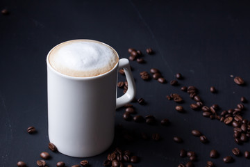 A mug of latte coffee on a black background