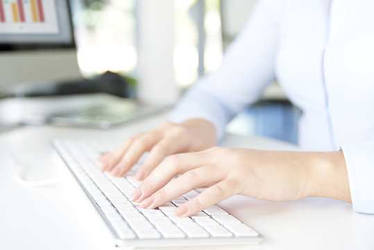 Typing on keyboard. Close-up image of a woman's hands typing on her computer keyboard while sitting at office and working online.