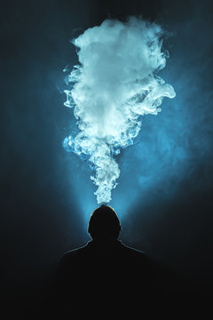 The man smoke a cigarette against the background of the bright light