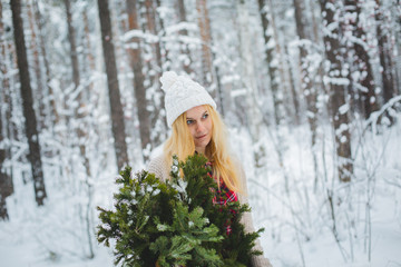 girl in winter forest holds branches in his hands