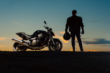 Fototapeta na wymiar Silhouette of man in leather outfit with motorbike