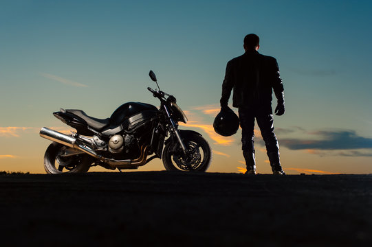 Fototapeta Silhouette of man in leather outfit with motorbike