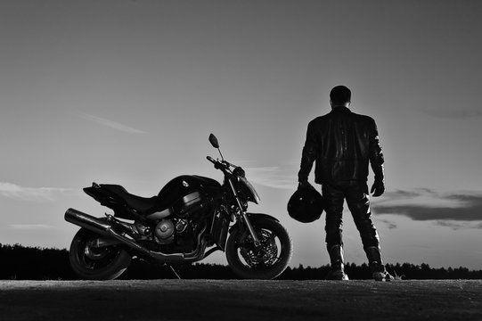 Fototapeta Silhouette of male biker standing next to bike