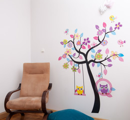 Handmade posters stuck tree with birds on the wall in children's room.