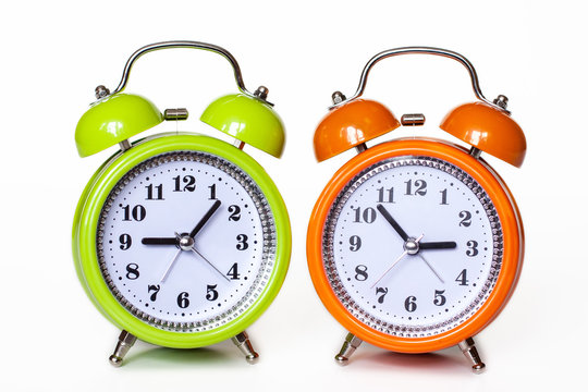 Two alarm clocks, green and orange, isolated on white background