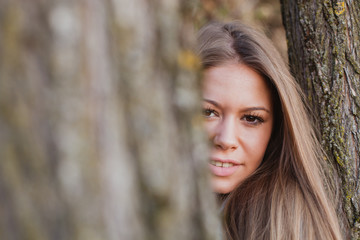 Beautiful woman behide to athe trunk of a tree