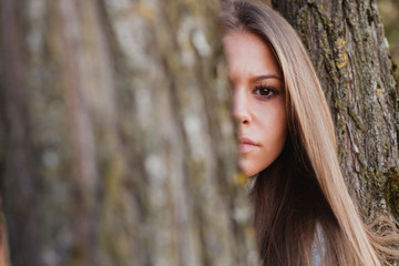 Beautiful woman behide to athe trunk of a tree