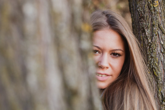 Beautiful woman behide to athe trunk of a tree