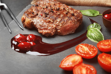 Tasty juicy steak with spices and sauce on slate plate