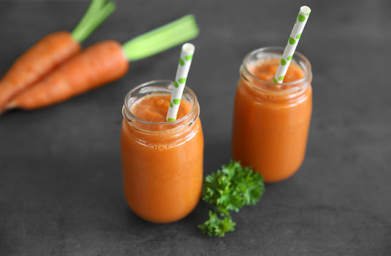 Fresh carrot juice with straw on table