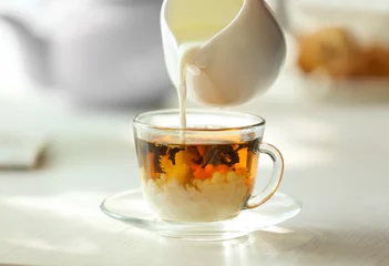 Crédence de cuisine en verre imprimé Theé Pouring milk in tea on table