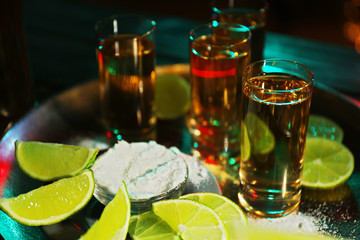 Gold tequila shot with lime and salt in bar