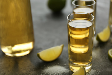 Gold tequila shots with lime and salt on gray table