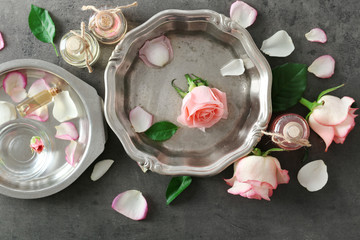 Fototapeta na wymiar Metal plate with aroma oil and flowers, top view