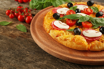 Delicious pizza with mushrooms, cherry tomatoes, olives and basil on wooden background